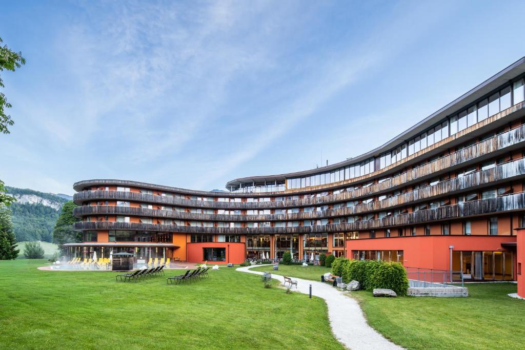 a large red building with a green lawn in front at Vivea Hotel Bad Goisern in Bad Goisern