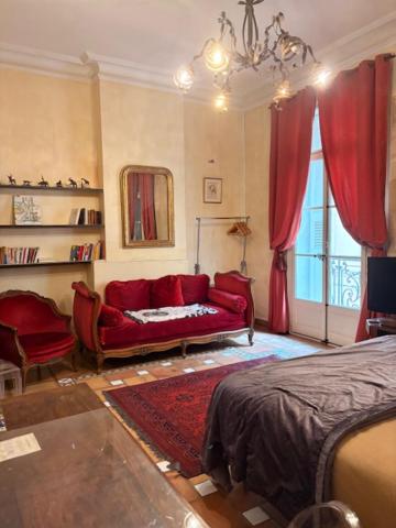 a living room with a red couch and a bed at Bartissol et Maillol in Perpignan