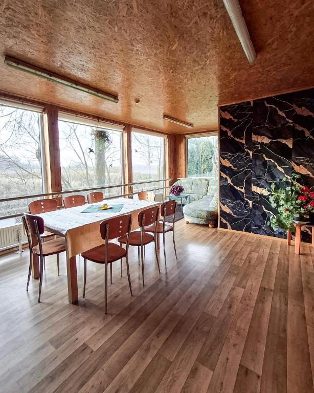 a dining room with a table and chairs and a stone wall at Sodyba prie Mūšos in Pamūšis