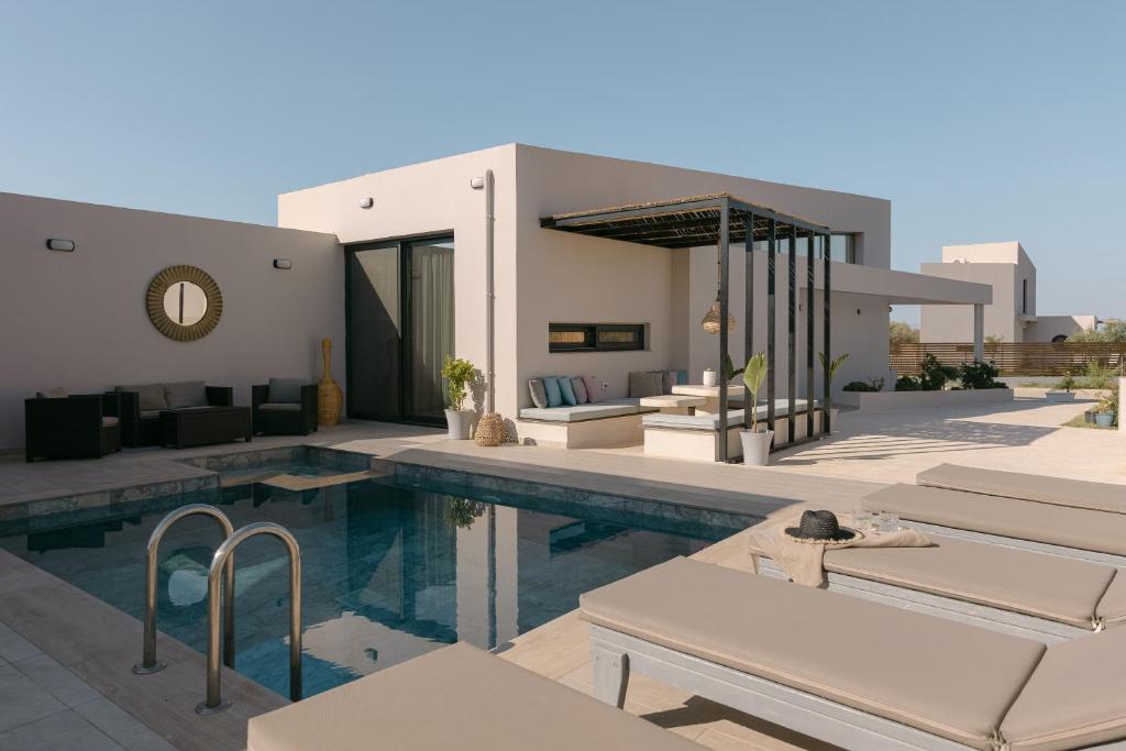 a swimming pool with chairs and a house at Unlimited Terra Villas, Charming Nature Escapes, By ThinkVilla in Hersonissos