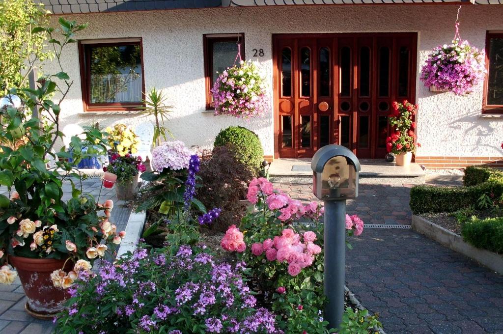 Un jardín con flores y un parquímetro frente a una casa. en Gerä Umige Ferienwohnung In Lay Am Moselhang, en Coblenza