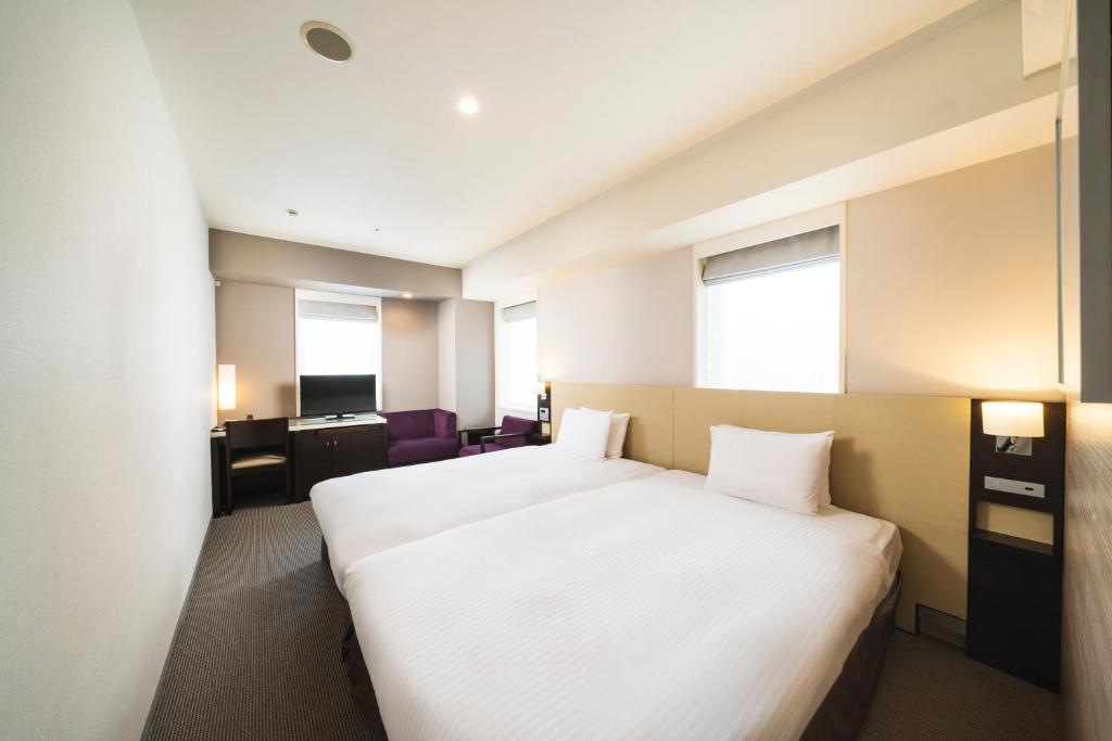 a hotel room with a bed and a desk at KOKO HOTEL Kobe Sannomiya in Kobe