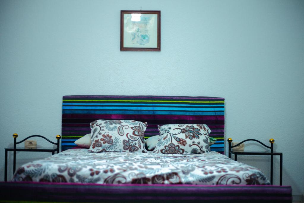 uma cama com duas almofadas e uma fotografia na parede em Dar KAMOUN em Houmt Souk