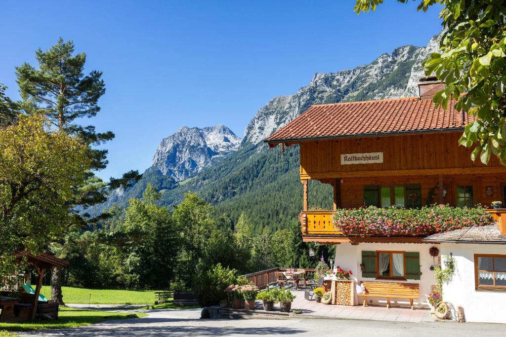 un edificio con balcón con montañas en el fondo en Gästehaus Kaltbachhäusl Garni, en Ramsau