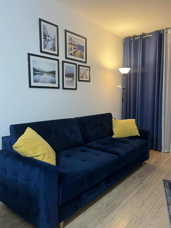 a blue couch with two yellow pillows in a living room at Apartament Enea z balkonem in Oleśnica