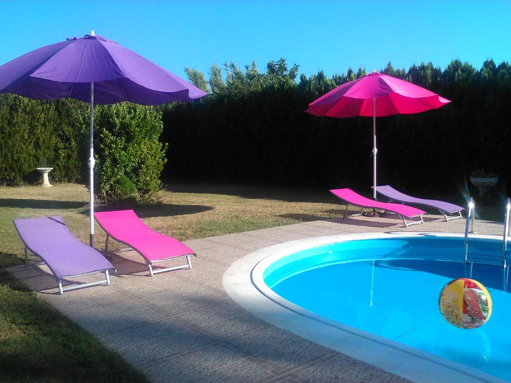 dos sombrillas y sillas púrpuras junto a una piscina en La Carapeteria en Arronches