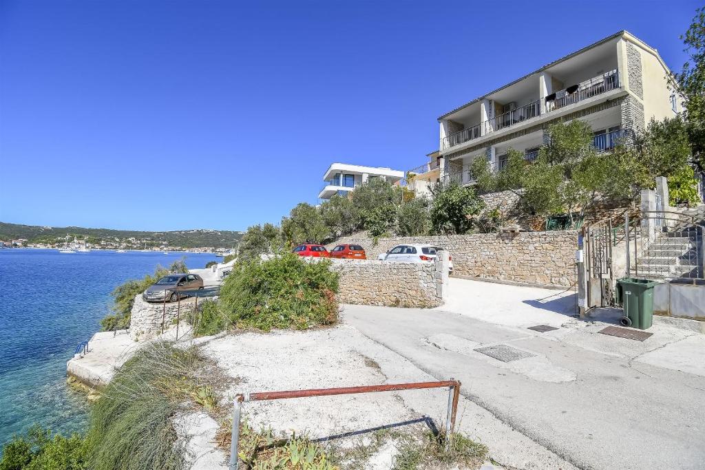 a building on a hill next to a body of water at Apartments Ivan in Vinišće