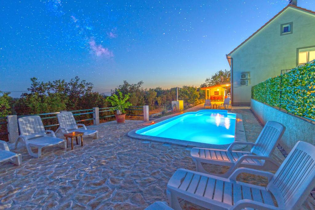 a swimming pool with lounge chairs next to a house at Ferienhaus In Opanci Mit Beheiztem Pool, Parkplatz in Lovreć