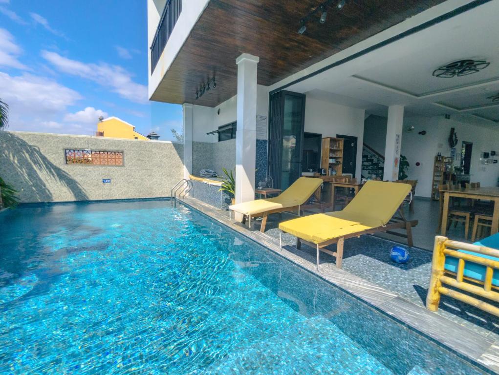 a swimming pool with two chairs and a house at EasyLife Villa Hội An in Tân Thành (1)