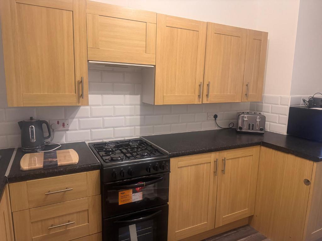 a kitchen with wooden cabinets and a stove top oven at Nobles Nest in Skegness