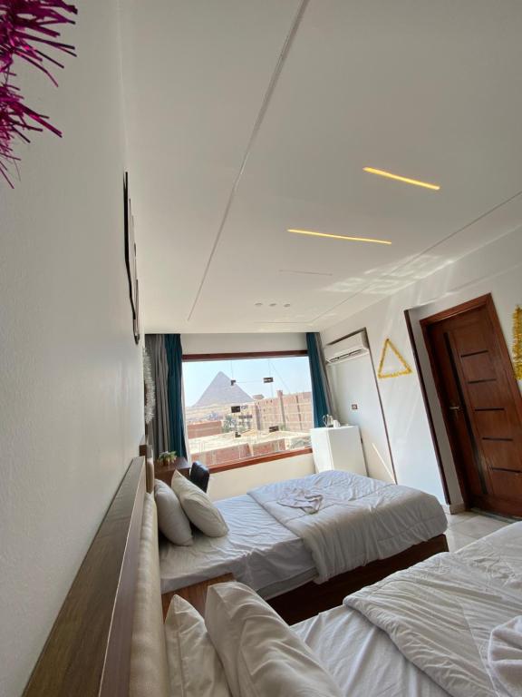 a bedroom with two beds and a large window at Pyramids Fort & free pickup shuttle in Cairo
