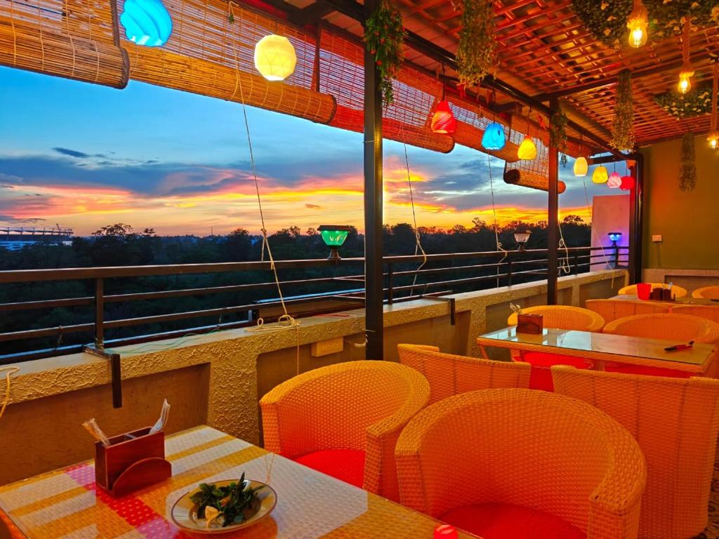 a restaurant with tables and chairs and a view of the sunset at Tathastu Stay in Dehradun