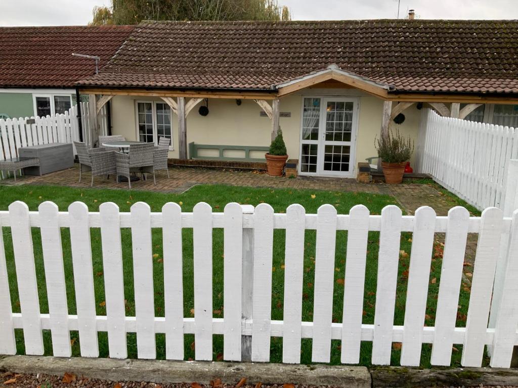 ein weißer Gartenzaun vor einem Haus in der Unterkunft woodpecker cottage at frog trotters cottages in Hartpury