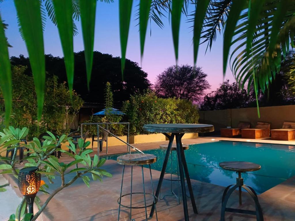 a pool with two bar stools and a table at Alampat Nest in Alwar