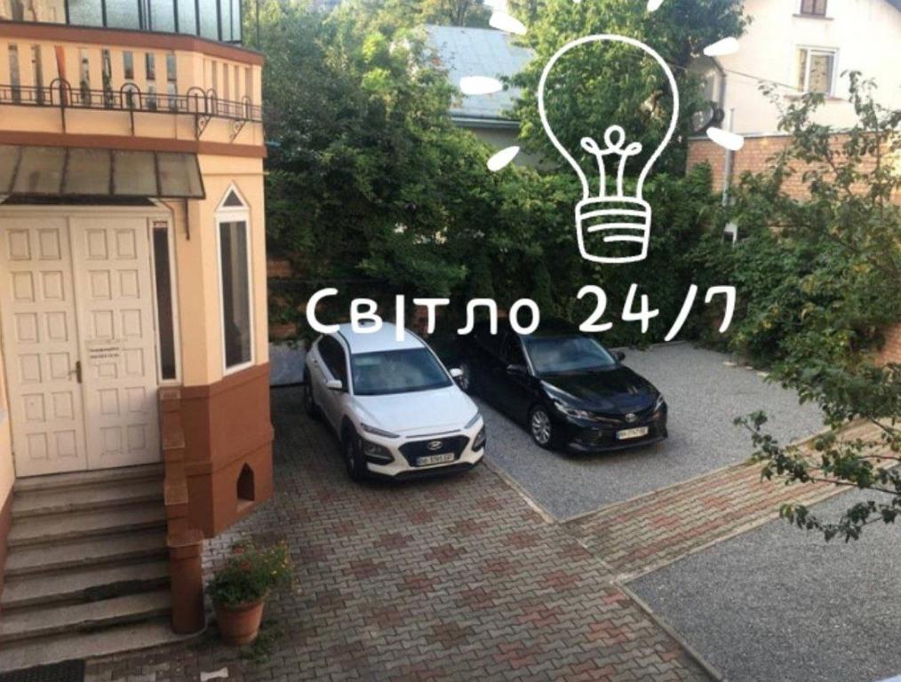 チェルニウツィーにあるНомер та Паркінг -Rooms Parking Світло Є 24 на 7!の電球のついた家の隣に駐車した2台の車