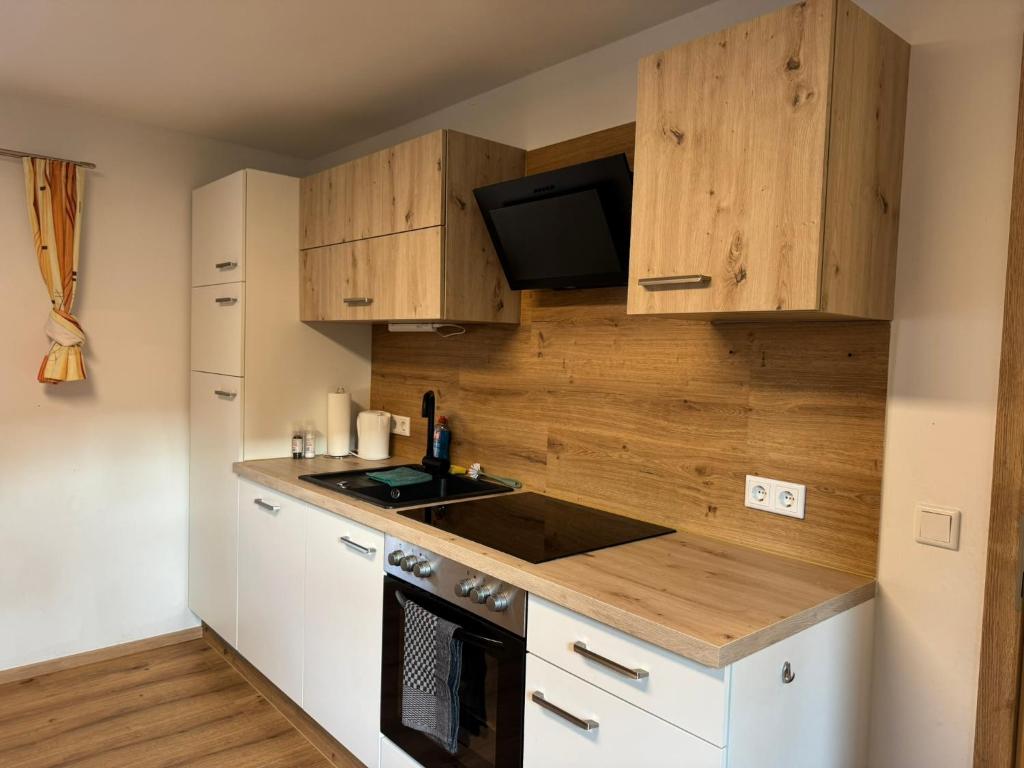 Ski und Wander Ferienhäuser Galsterberg-Blick Pruggern - Schladming-Dachstein في Michaelerberg: مطبخ مع خزائن خشبية ومغسلة وموقد