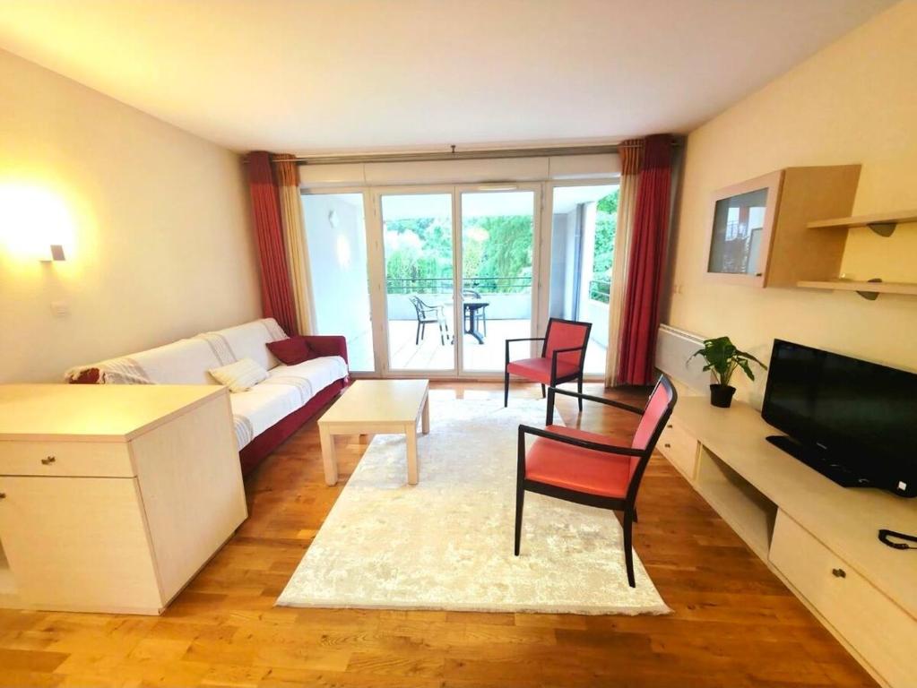a living room with a couch and chairs and a television at Spacious N3, quiet,great location in Divonne-les-Bains