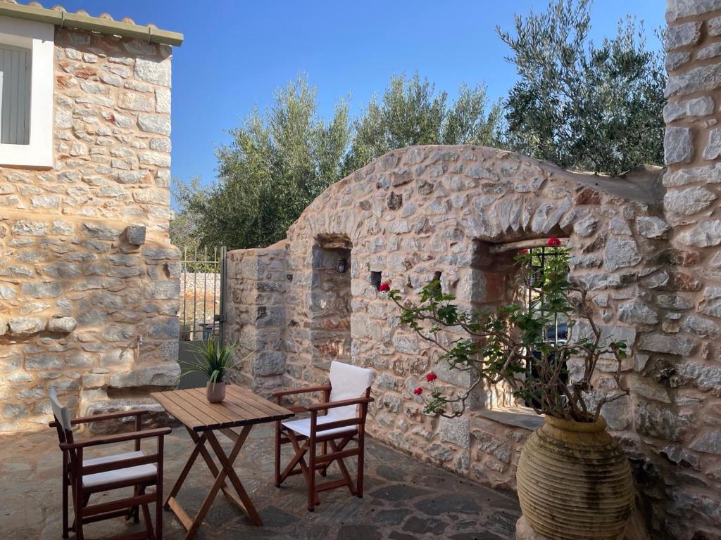 a patio with a table and chairs and a stone wall at Rose Home in Areopoli