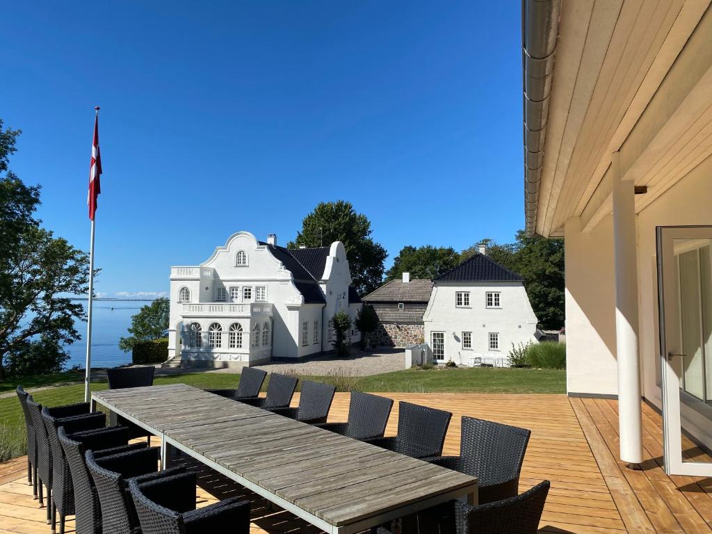 a wooden table and chairs on a deck with a house at Johanneberg in Vordingborg