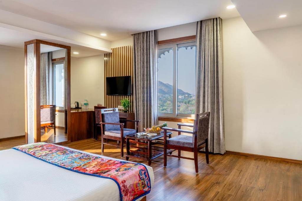 a hotel room with a bed and a desk and a table at Hotel Paandora Grand,Udaipur in Udaipur