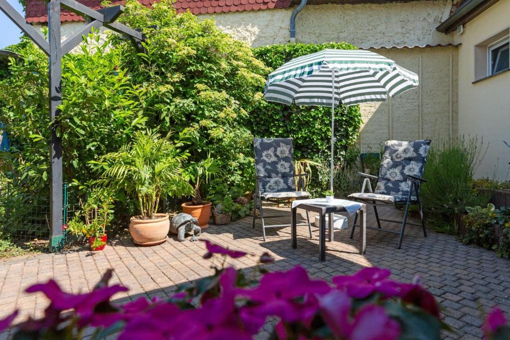 een patio met 2 stoelen, een parasol en bloemen bij Appartement In Süd in Dessau