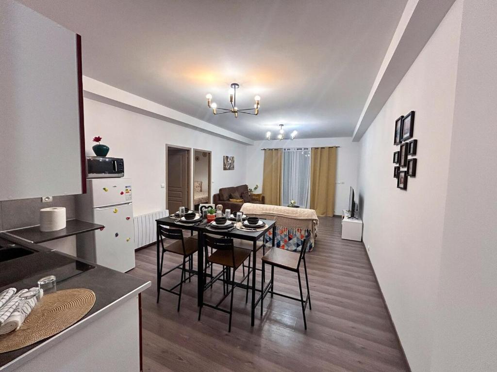 eine Küche und ein Wohnzimmer mit Tisch und Stühlen in der Unterkunft Appartement avec 2 chambres Jardin privé parking gratuit in Clermont-Ferrand