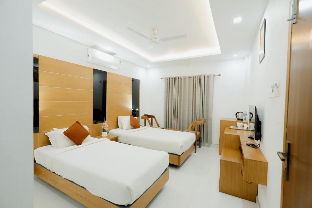 a hotel room with two beds and a desk at Paarijatham Residency in Guruvāyūr