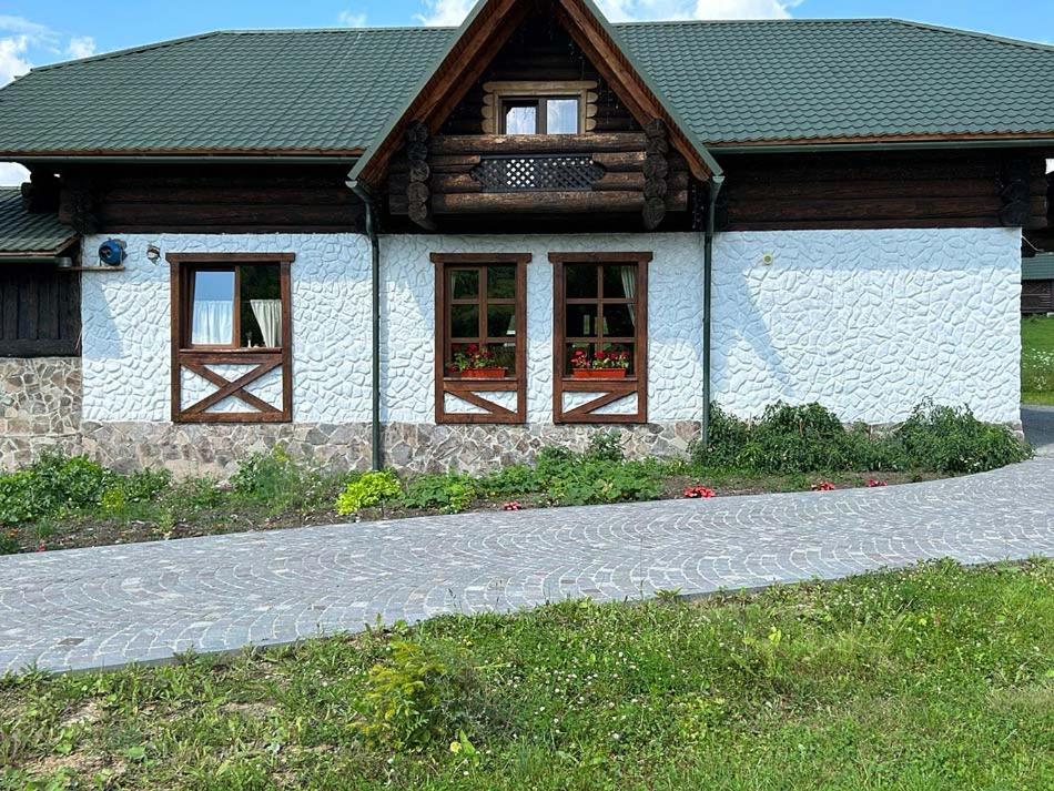 a house with two windows and a stone driveway at Котедж ЛАТОРИЦЯ in Laterka