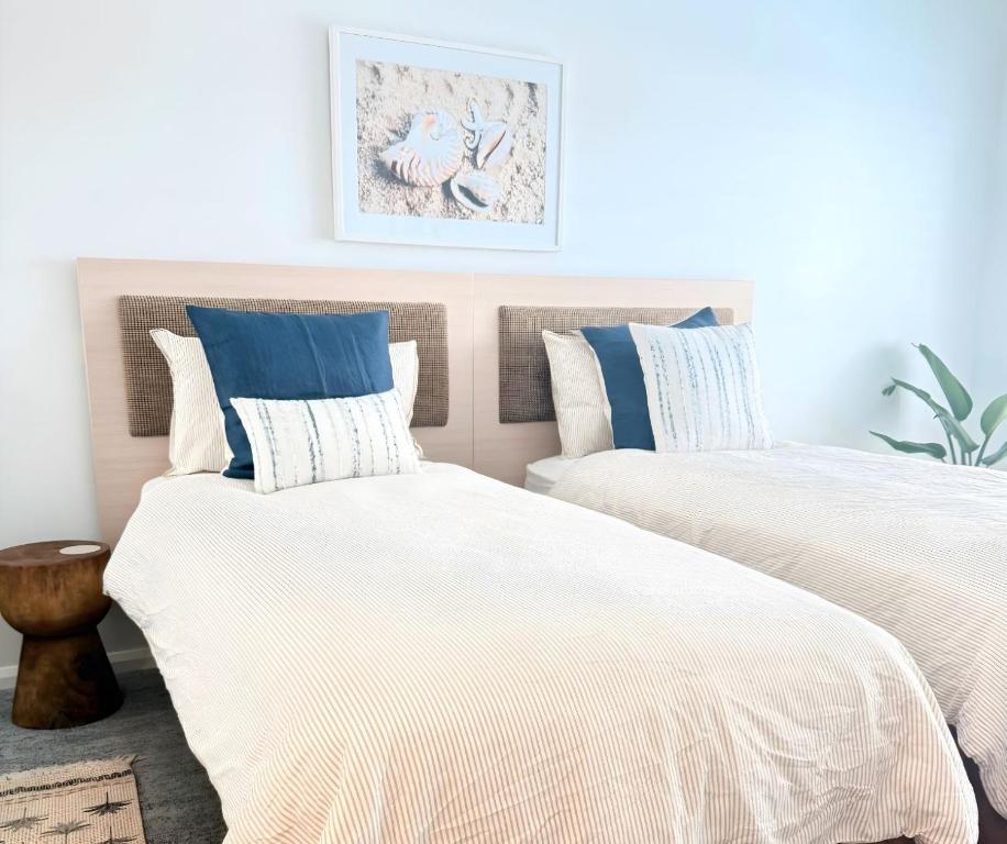 two beds with white and blue pillows in a bedroom at Studio Lagoon Apartment in Salamander Bay
