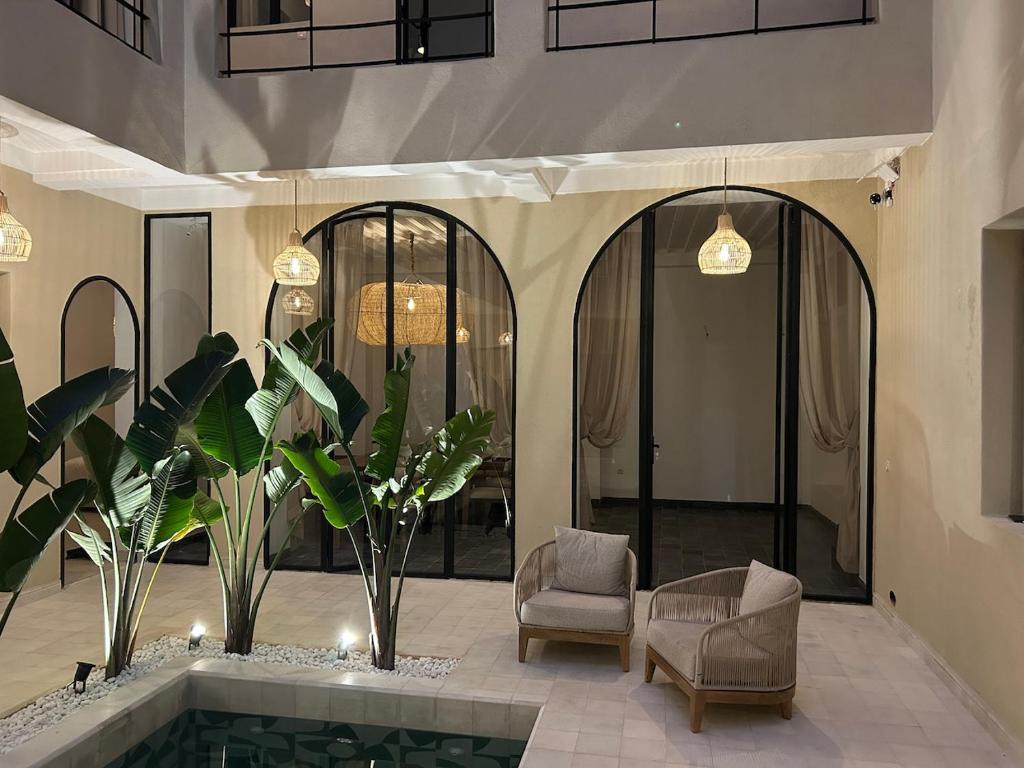 a lobby with a pool and two chairs and plants at Riad A l'Ombre du Palais in Oulad Akkou