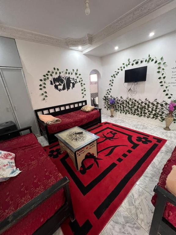 ein Wohnzimmer mit 2 Betten und einem roten Teppich in der Unterkunft R feto house in Al Ḩārah al Kabīrah