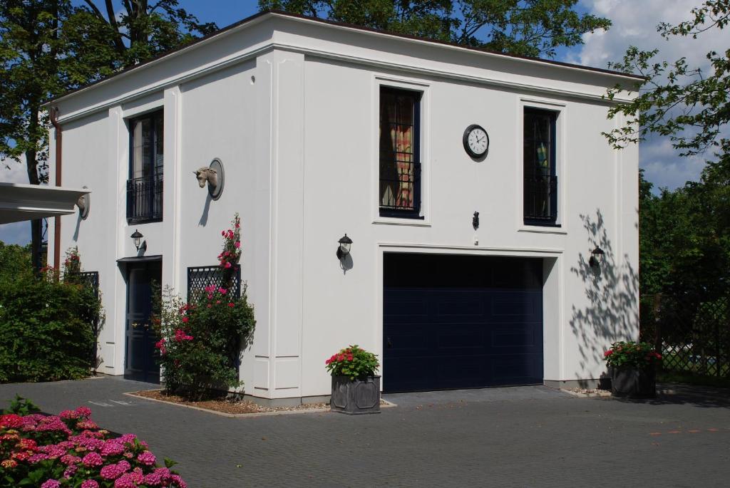 ein weißes Gebäude mit einer Garage mit einer Uhr drauf in der Unterkunft Ferienwohnung für 3 Personen ca 70 m in Swantow, Ostseeküste Deutschland Rügen in Poseritz