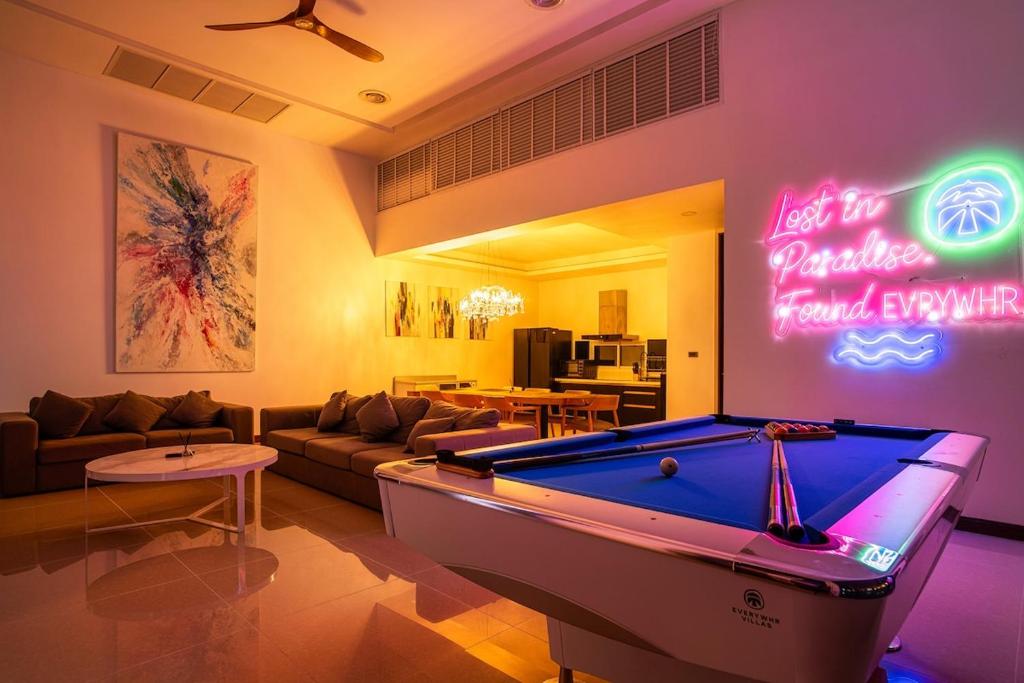 ein Wohnzimmer mit Billardtisch und Leuchtreklame in der Unterkunft Villa Astra - 4BR Entertainment Pool Villa, Rawai in Ban Kata