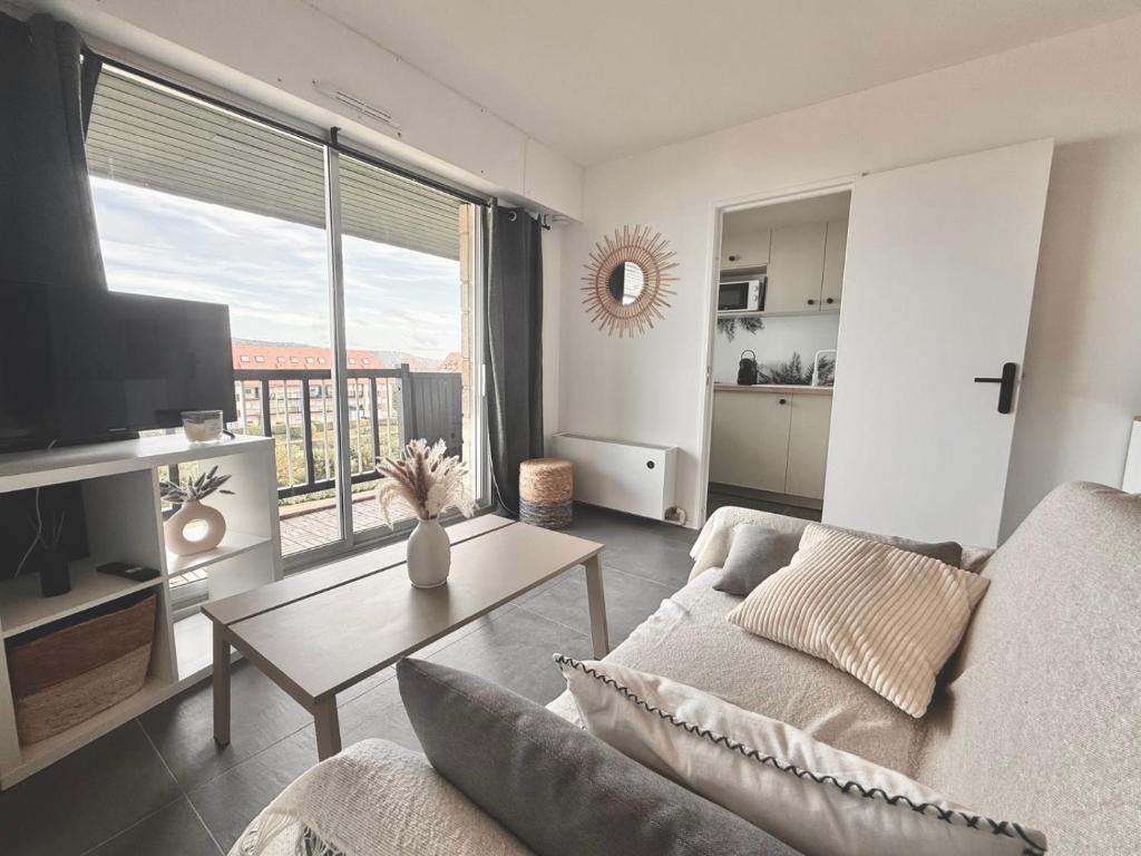 a living room with a couch and a table at Sunset View , Studio , Parking & Wifi in Villers-sur-Mer