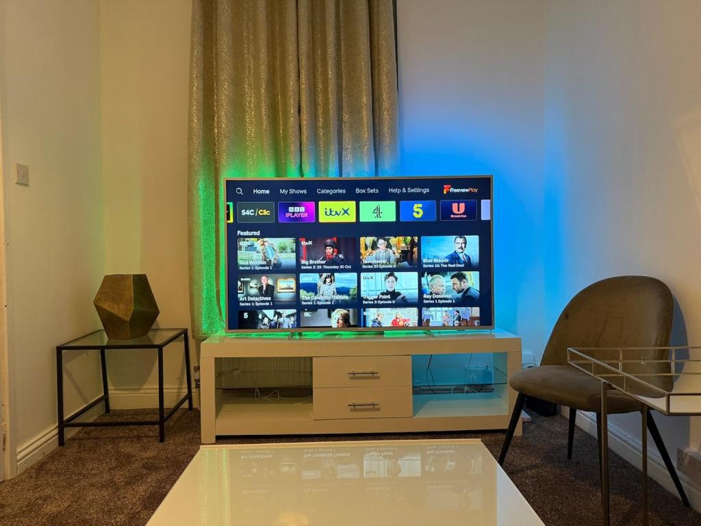 ein Flachbildfernseher auf einem Ständer mit zwei Stühlen in der Unterkunft City Centre 2 Bed with Ensuite Rooms Wakefield in Wakefield