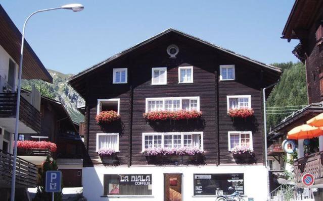 a large black house with flowers in front of it at Fewo Mit Blick Auf Die Berge in Sedrun