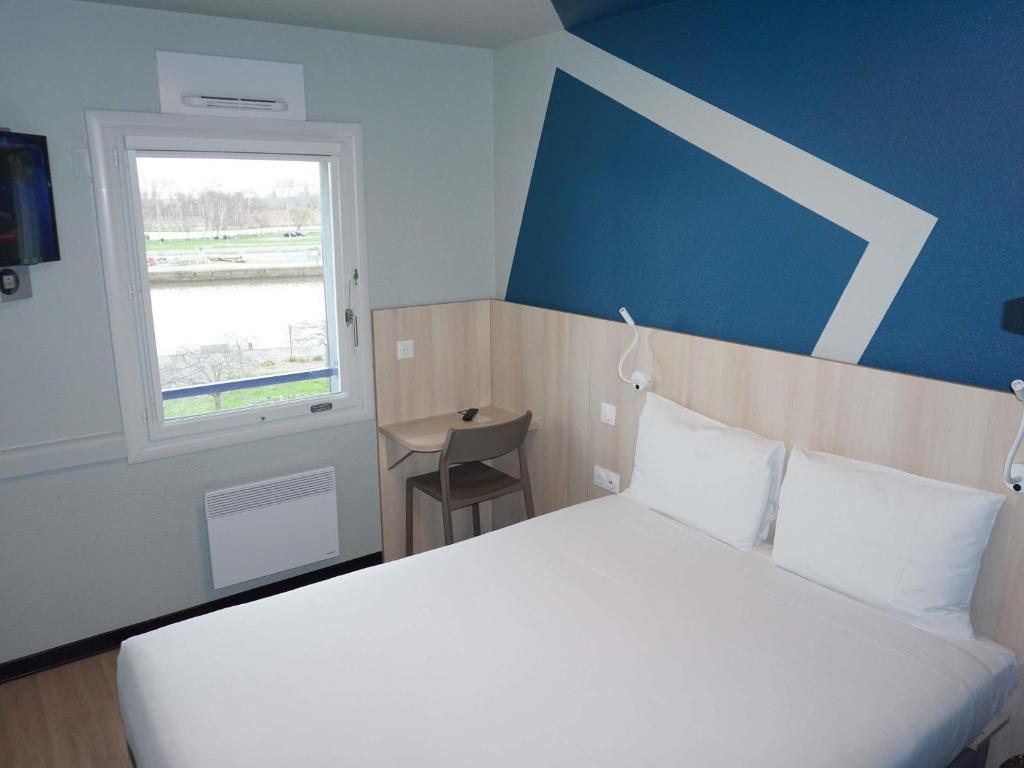 Un dormitorio con una cama blanca y una ventana. en ibis budget Honfleur Centre, en Honfleur