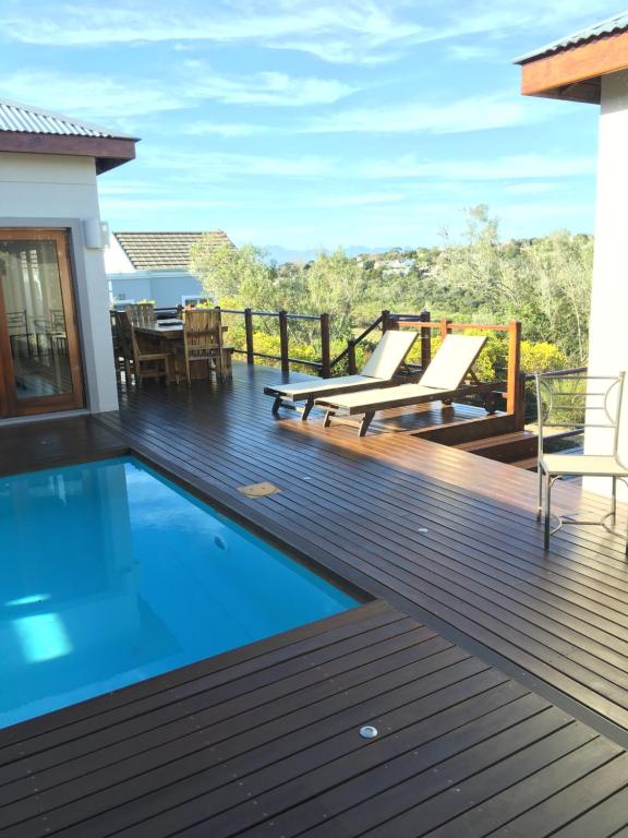 a deck with a swimming pool and two lounge chairs at Plettenberg Bay Getaway in Plettenberg Bay