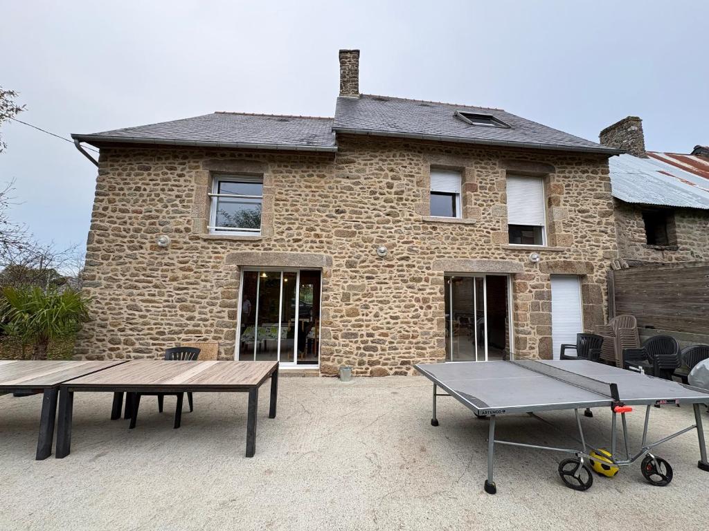 a brick house with two picnic tables in front of it at Le Noisetier in Baguer-Pican