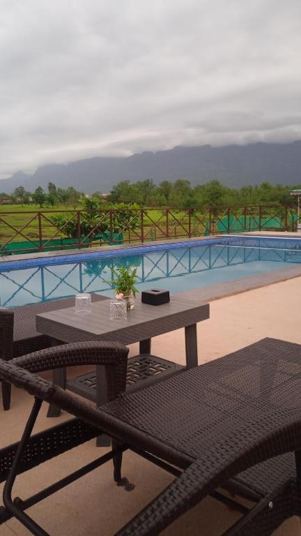 a picnic table and chairs next to a pool at The Malshej Mist in Ghātghar
