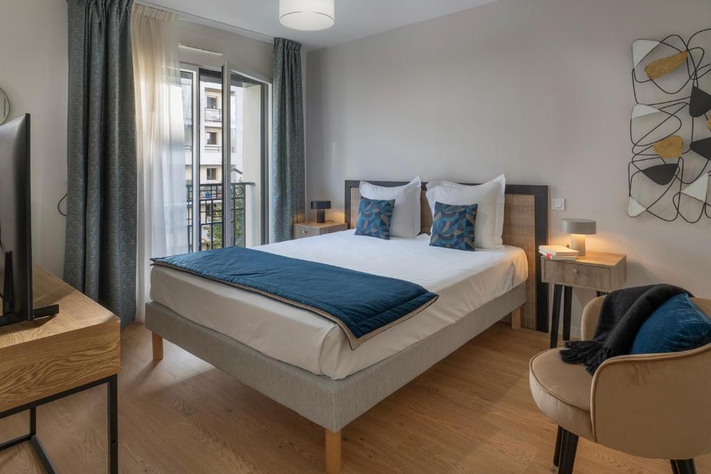 a bedroom with a bed with blue pillows at Domitys Le 225 in Levallois-Perret