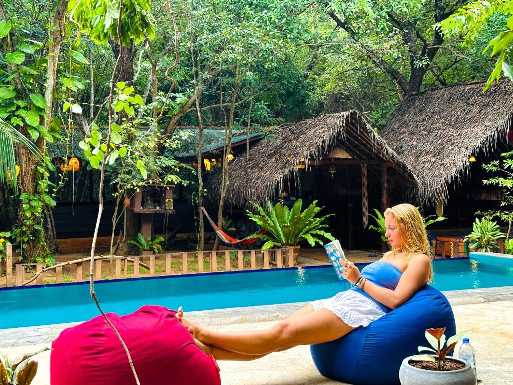 Una mujer sentada en una pelota inflable junto a una piscina en Jungle Host Hostel And Tree House, en Sigiriya