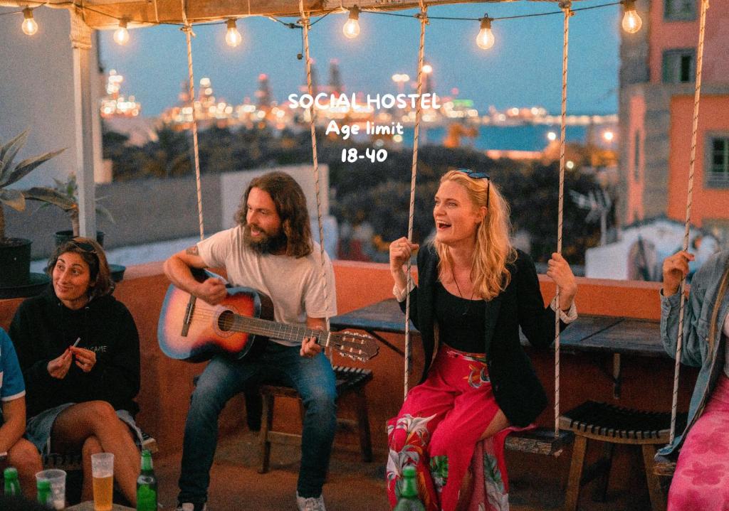 a group of people sitting on a swing at Doña Rose Old Town Hostel in Las Palmas de Gran Canaria