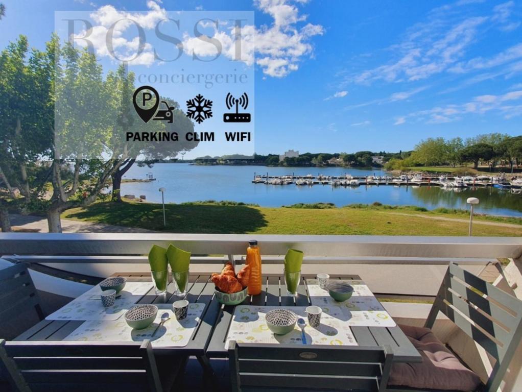 a table on a patio with a view of a lake at L'OLYMPE VUE LAC PARKING CLIM WIFI - ROSSIconciergerie - Linge inclus in La Grande-Motte