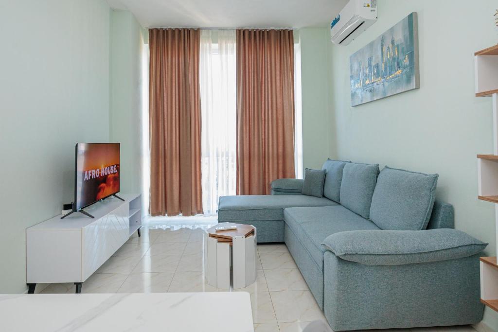 a living room with a blue couch and a tv at Luxury Apartment with Parking in Tirana