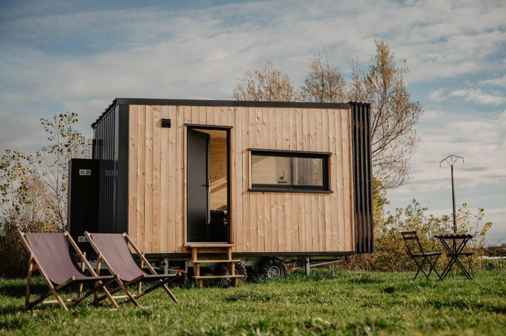 a tiny house sitting in a field with two chairs at Homnest - Loge insolite au coeur d'un ranch - Balade à cheval in Espinasse-Vozelle
