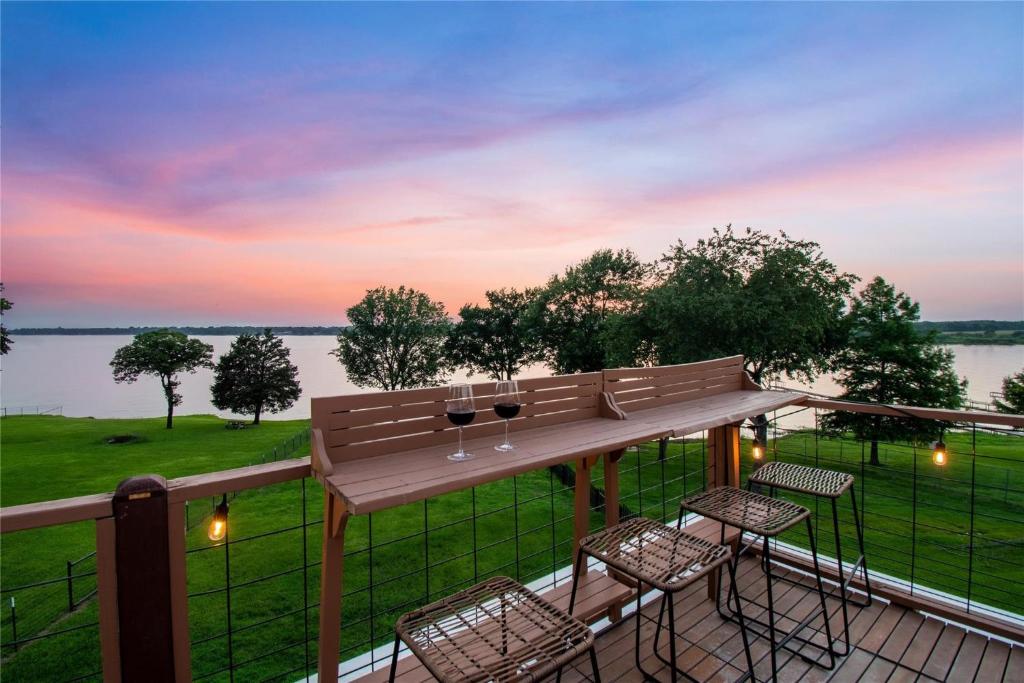 a deck with chairs and a table with wine glasses at Modern Lakeside Paradise - Waterfront 2 Patios home in Mabank