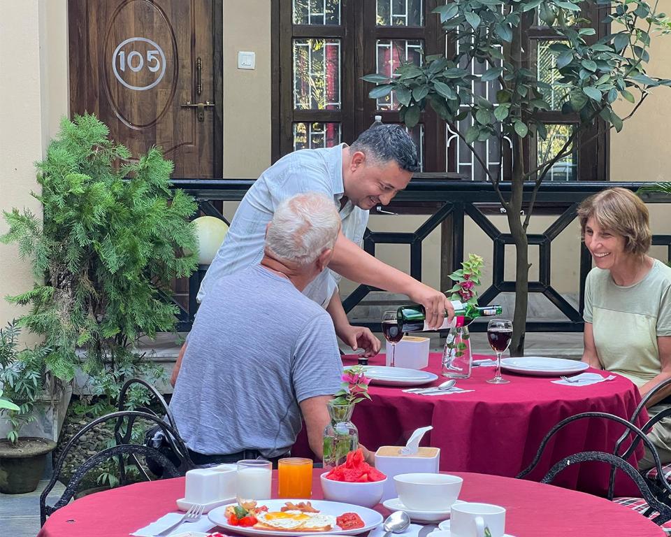 Um homem a servir um copo de vinho à mesa. em Chitwan Park Village em Sauraha