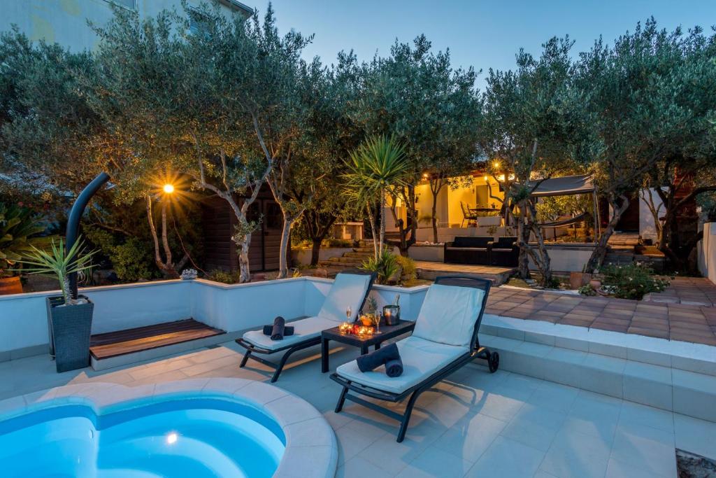 een patio met stoelen en 's nachts een zwembad bij Komplex Oliva Mit Pool Und Großem Garten in Stari Grad