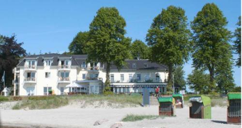 a large white building on a beach with trees at Hof Sierksdorf in Sierksdorf